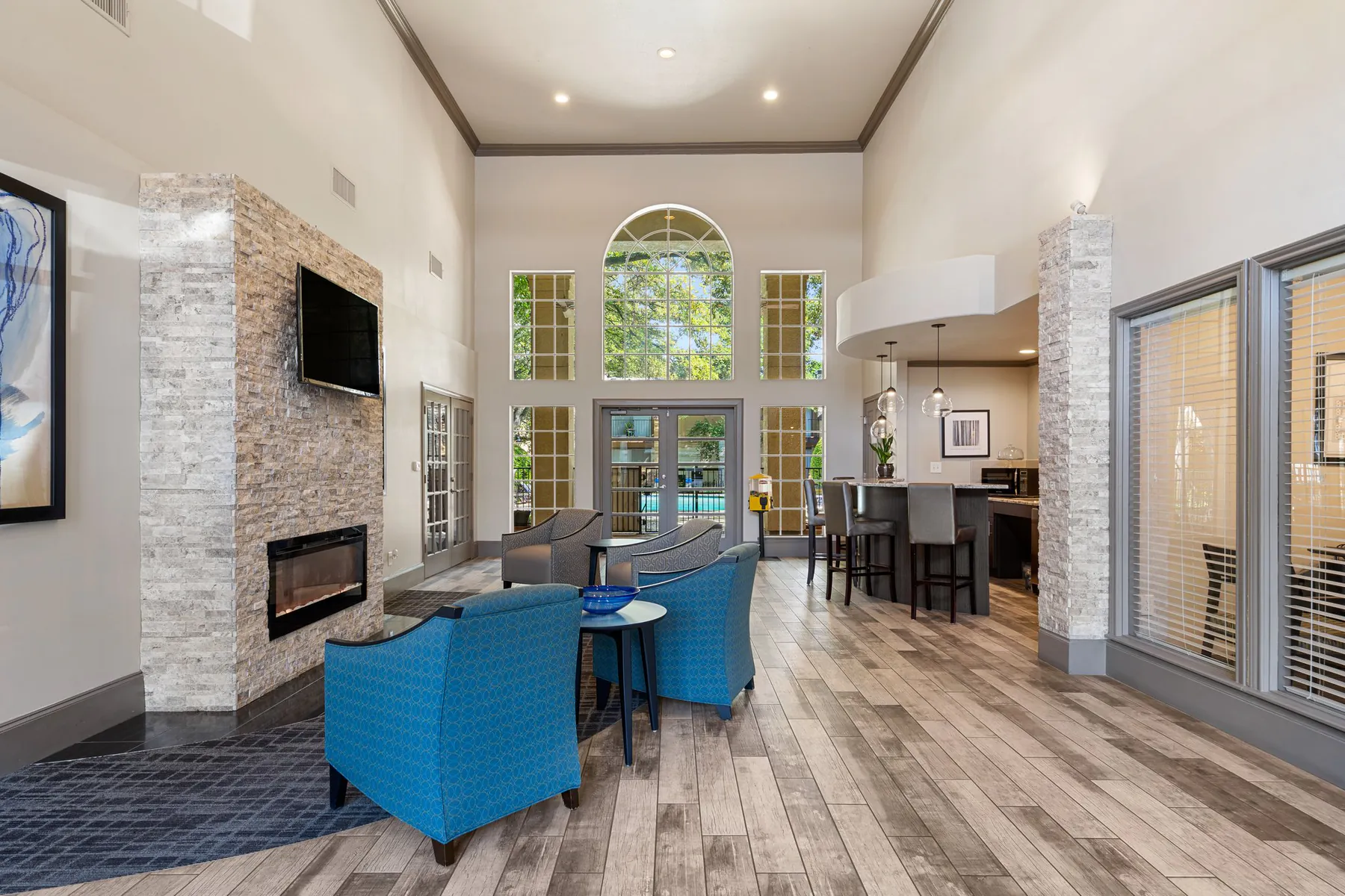 Clubhouse lounge with stone fireplace, seating, and kitchen bar at Regal Court