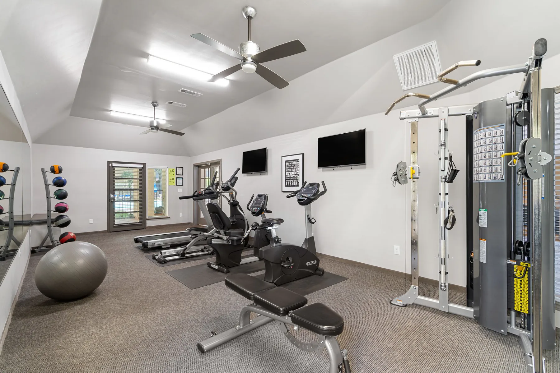 Fitness center with a treadmill, exercise bikes, and a cable weight machine at Regal Court