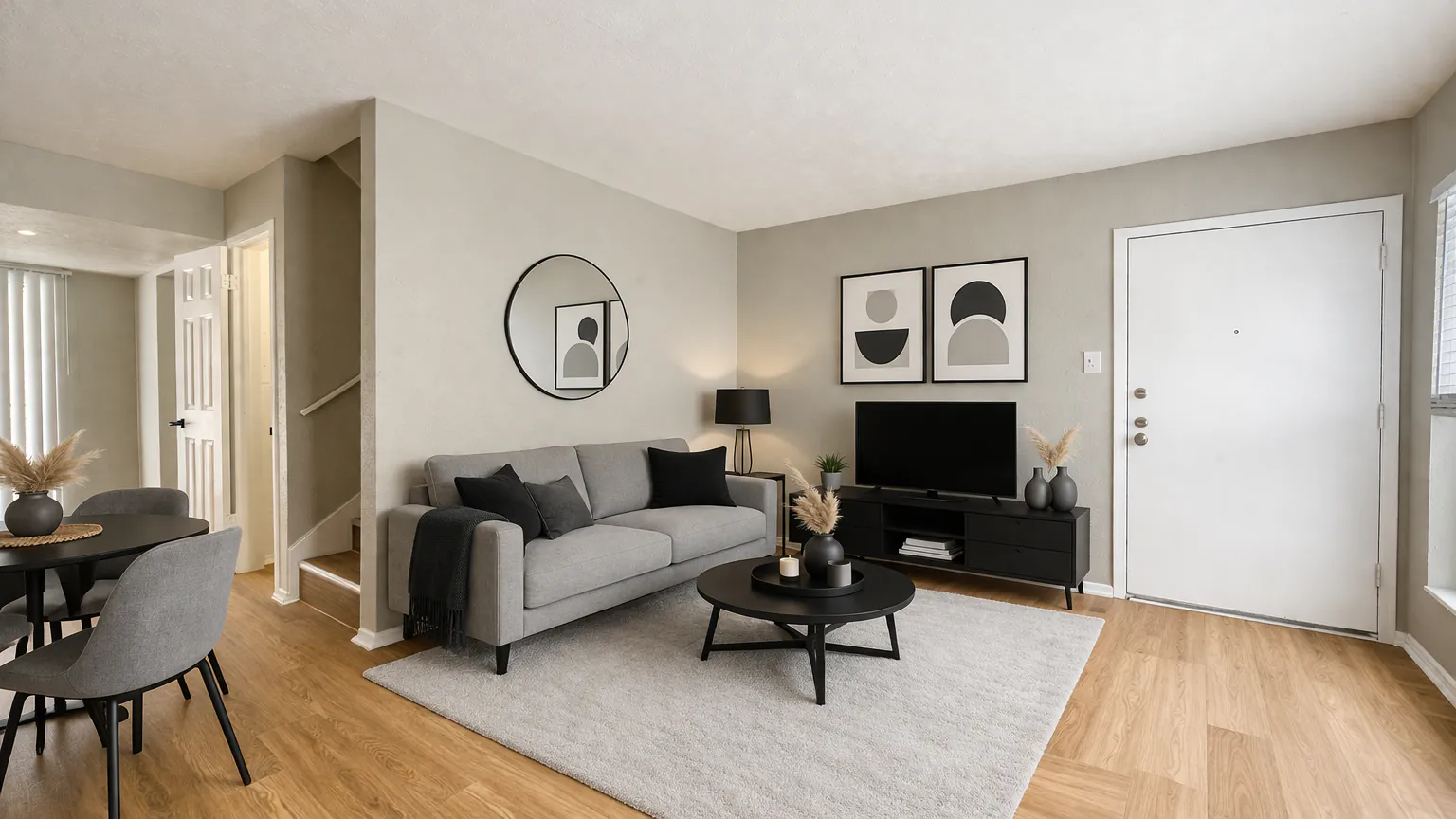 Furnished townhome living room with the staircase and front door beyond, at Regal Court