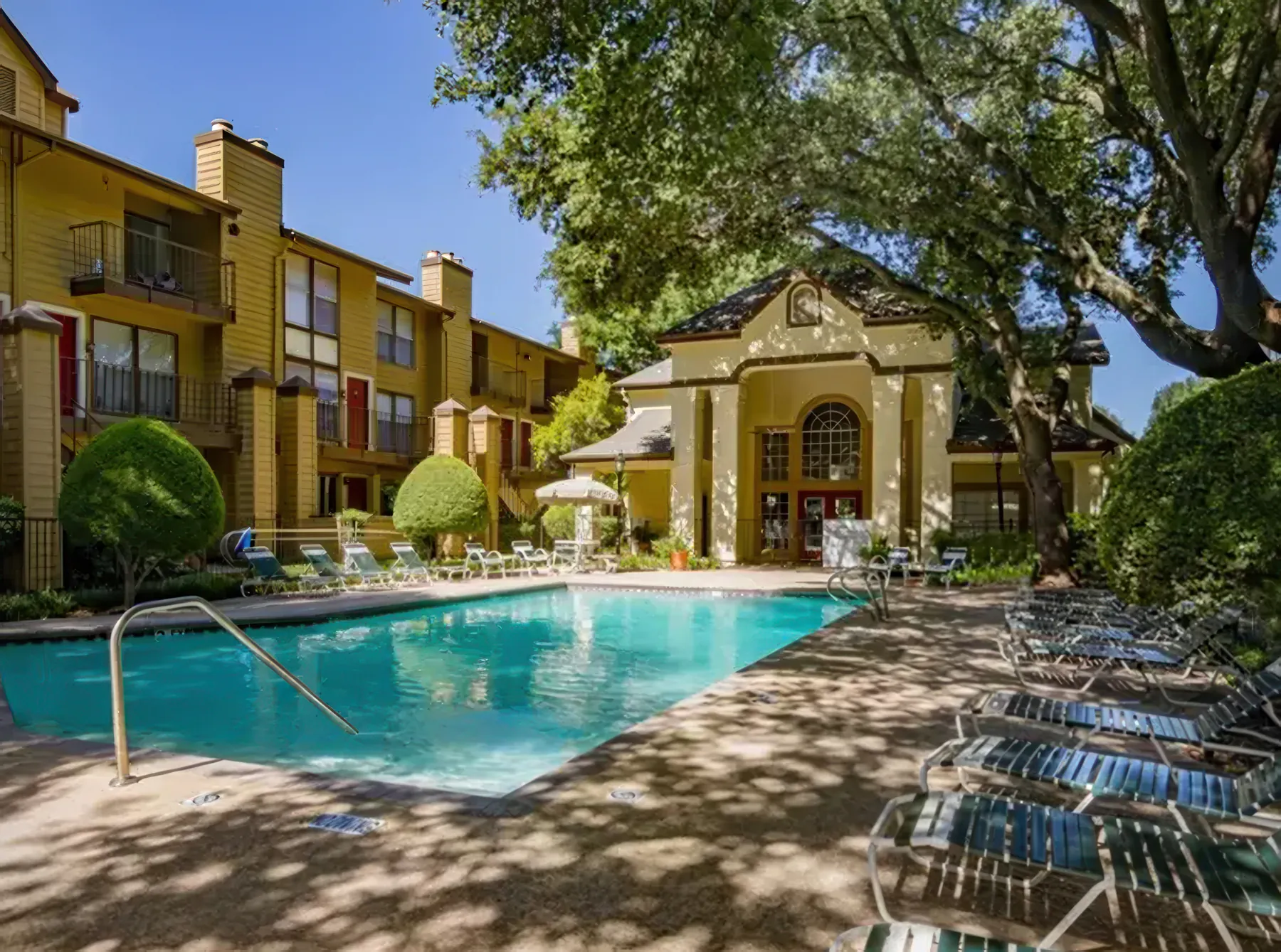 Swimming pool and clubhouse at Regal Court Apartments, shaded by mature trees