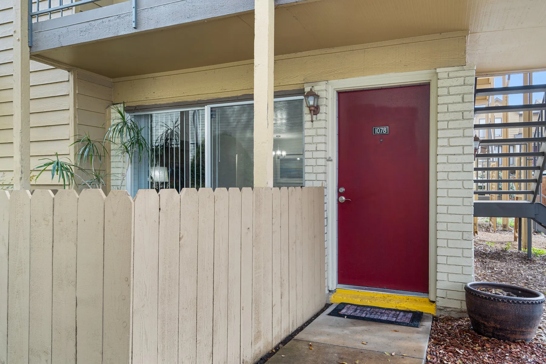 Red front door with a fenced private patio at Regal Court